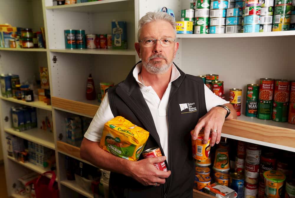 CEO of Hobart City Mission John Stubley standing in front of a pantry