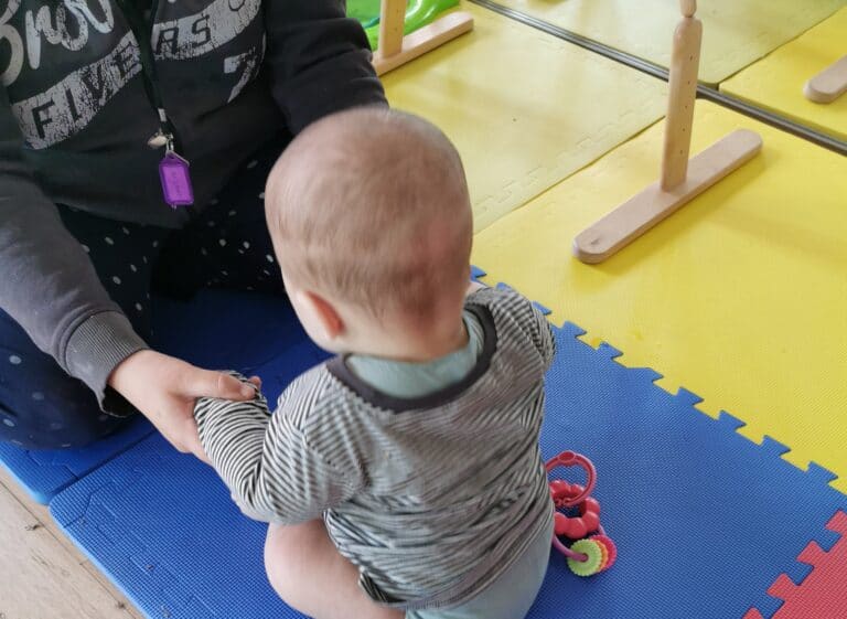 baby sitting on floor on playroom floor