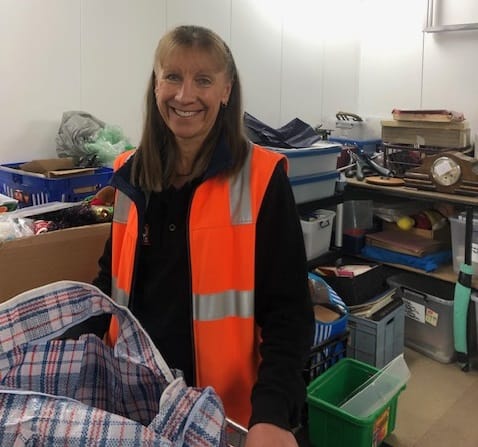 woman in hi-vis vest in a warehouse smiling and looking at camera