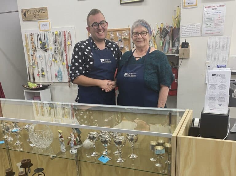 man and woman shaking hands behind a shop counter in an op shop