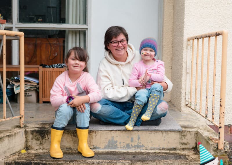 woman and her two children smiling at the camera on steps